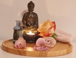 Buddha auf Tablett mit Aromaöl und Blumen